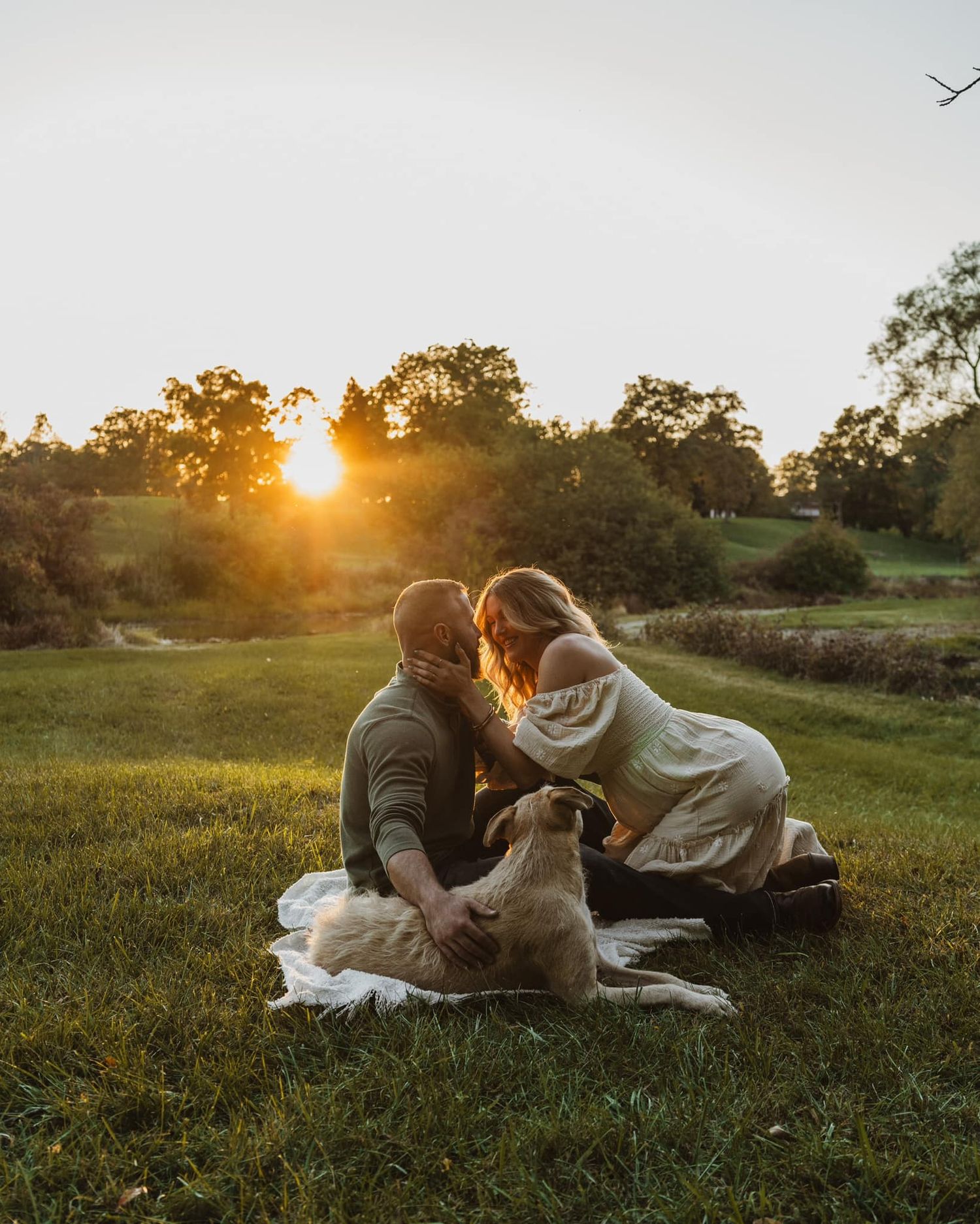 Couple lounging on blanket in golden sunset field.