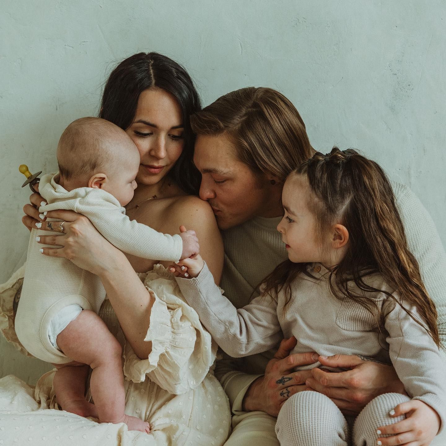 Tender family moments captured in soft, intimate poses against a light background.