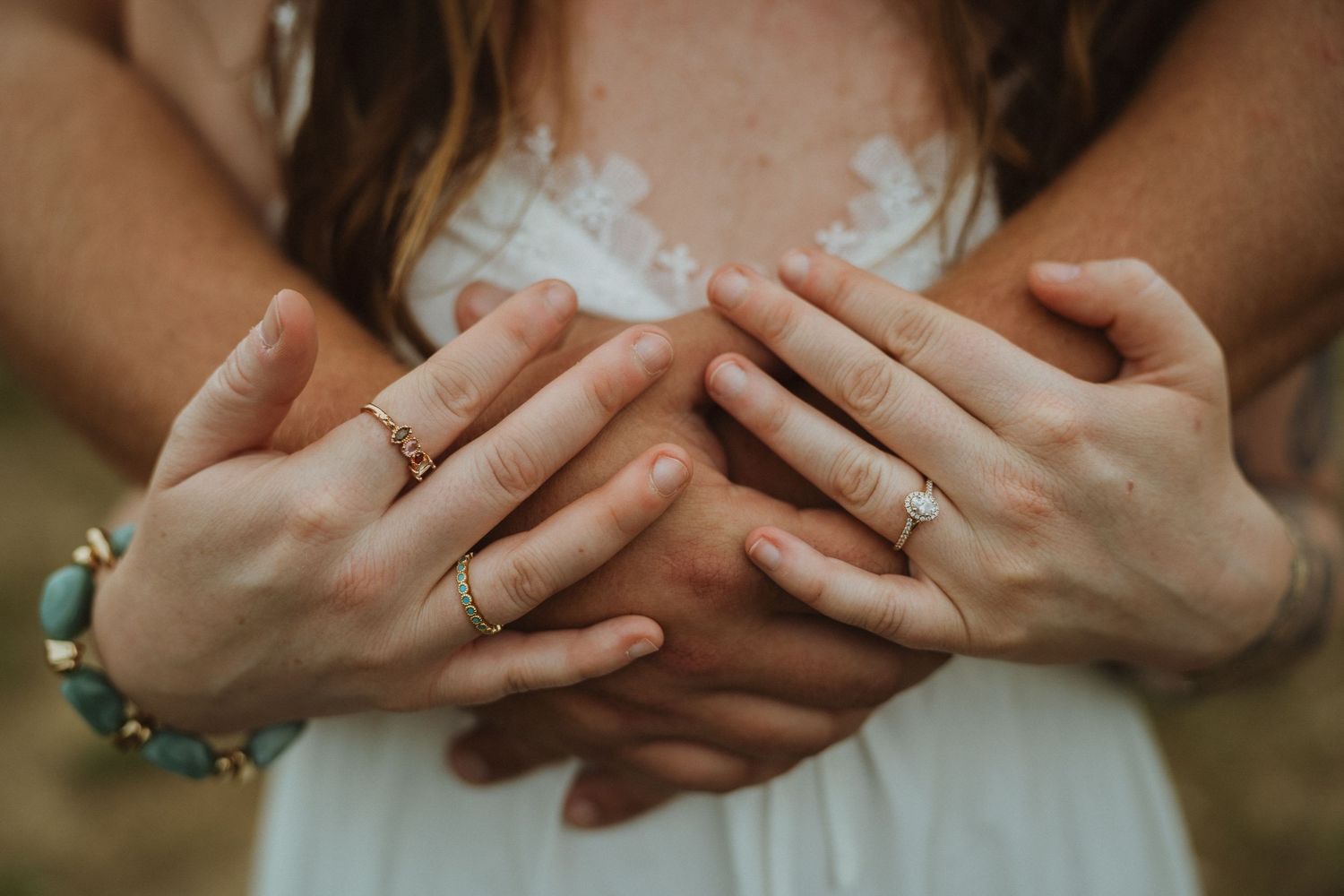 Close-up of couple's hands intertwined, wearing wedding rings, with a turquoise bracelet visible.