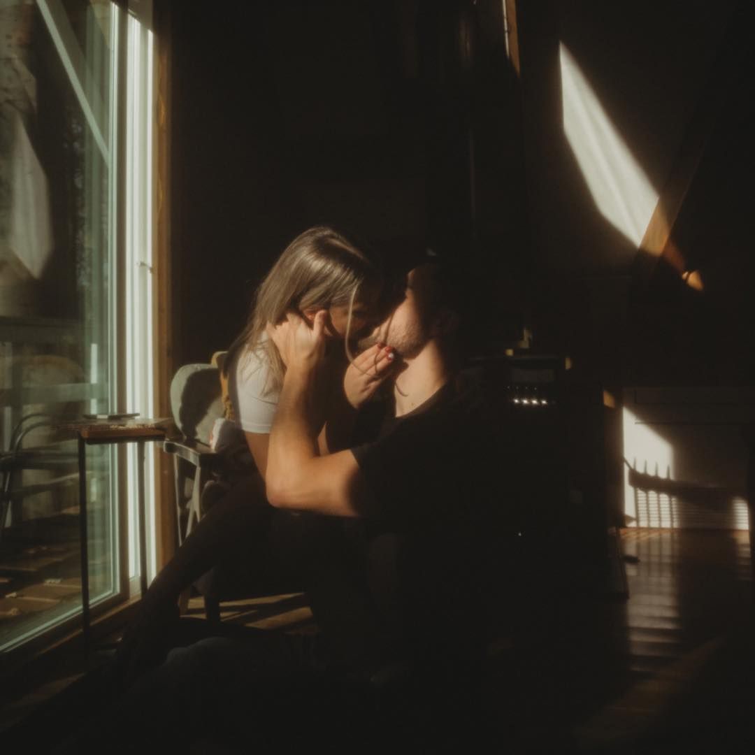 Moody silhouettes against window light creating dramatic shadows in a dark room.