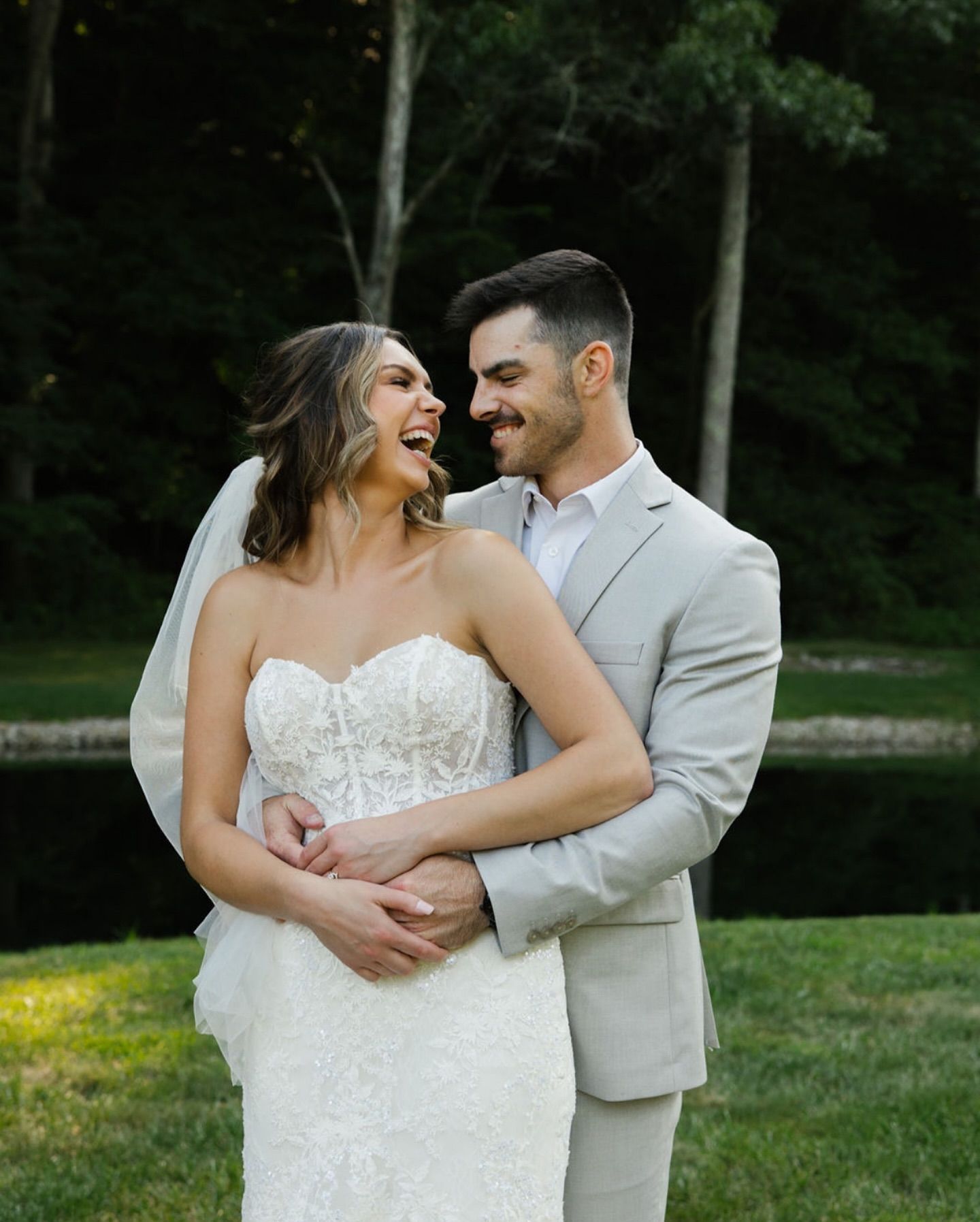 A joyful couple shares a candid moment together outdoors during their wedding celebration.