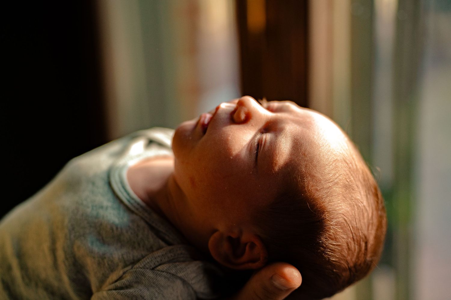 Close-up of a peaceful sleeping newborn baby held gently in a parent's hands.