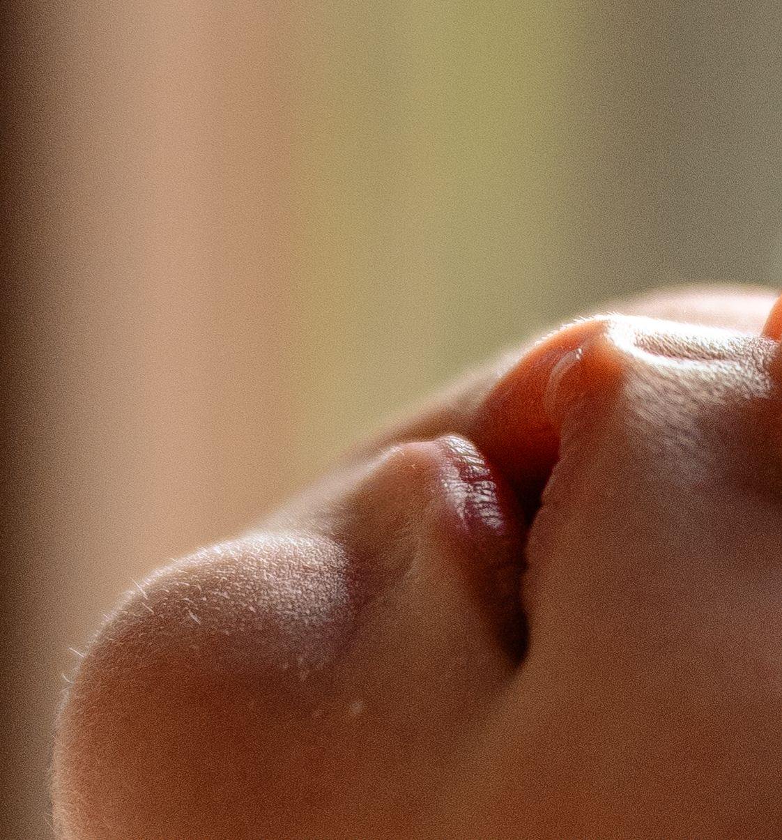 Close-up macro photo of a baby's nose and lips, showing delicate skin texture in soft natural light.