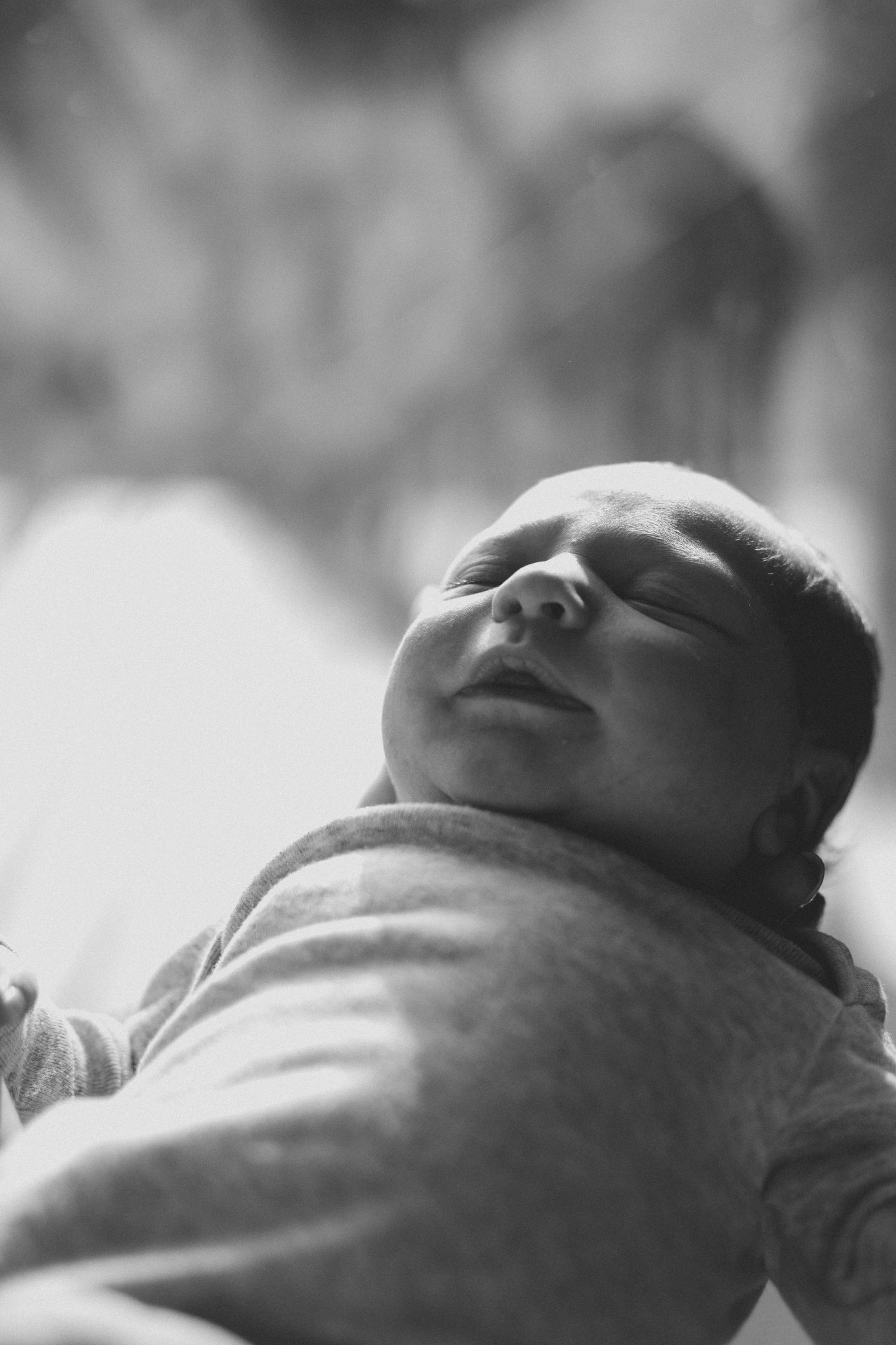 Black and white photo of a peaceful sleeping newborn baby wrapped in a soft blanket.