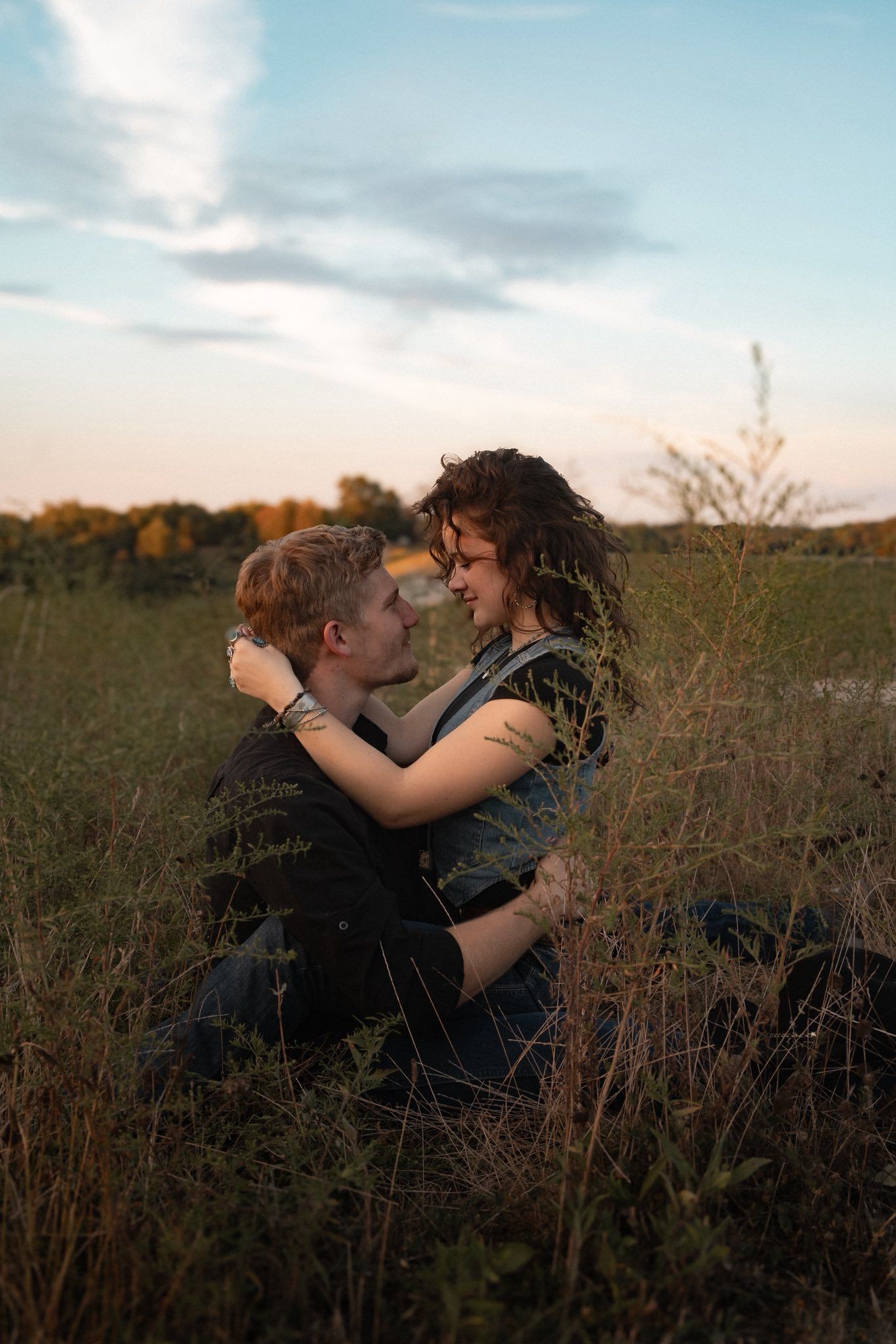 Romantic couple embracing in tall grass during golden hour.