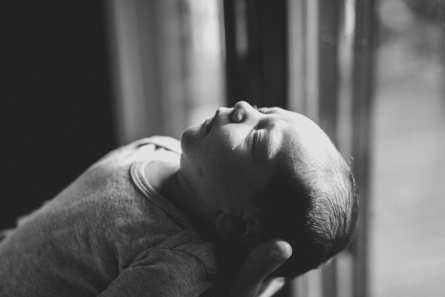 Black and white close-up portrait of peaceful sleeping newborn baby wrapped in soft swaddle.