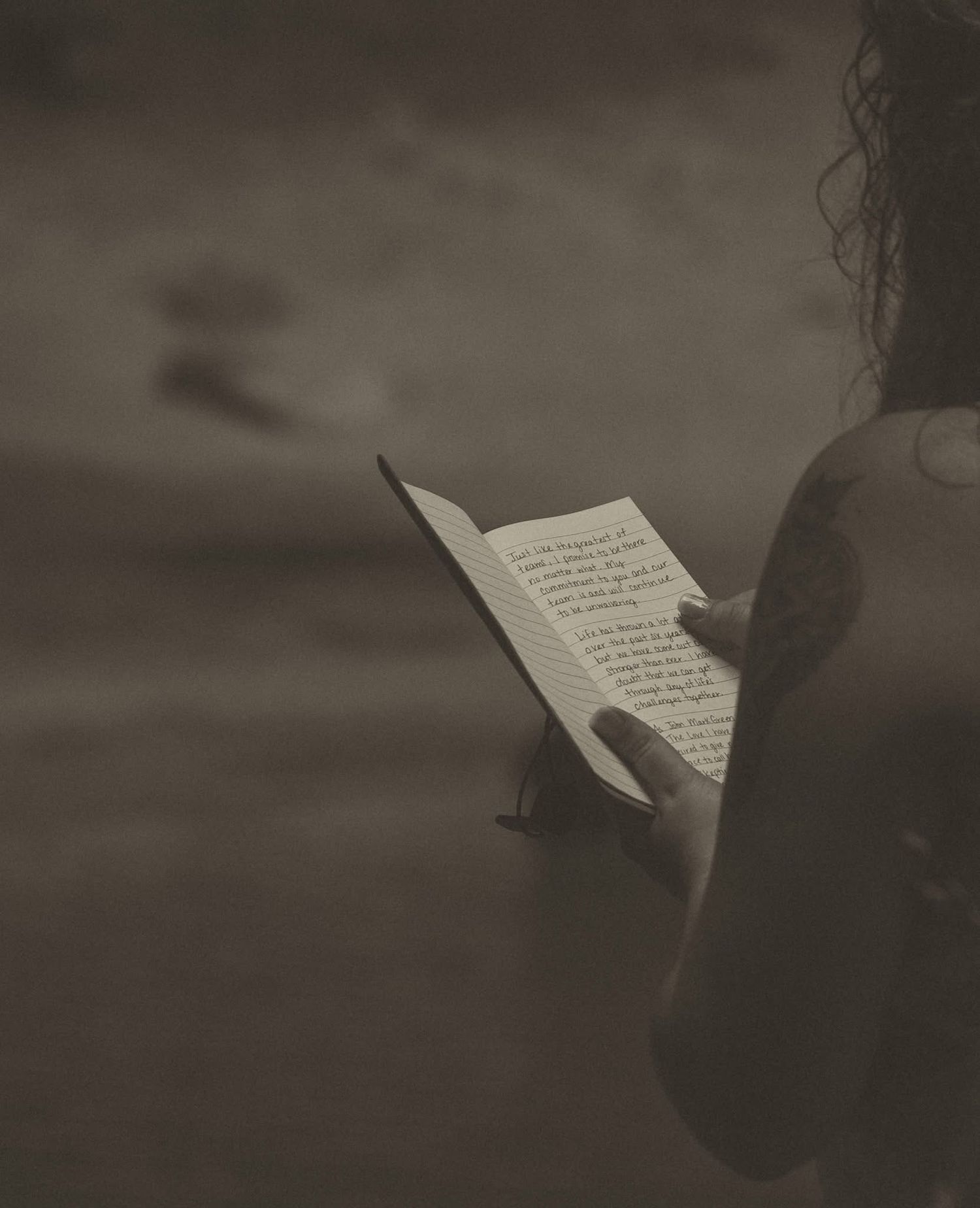 Close-up of handwritten letter or note being read in dramatic lighting.