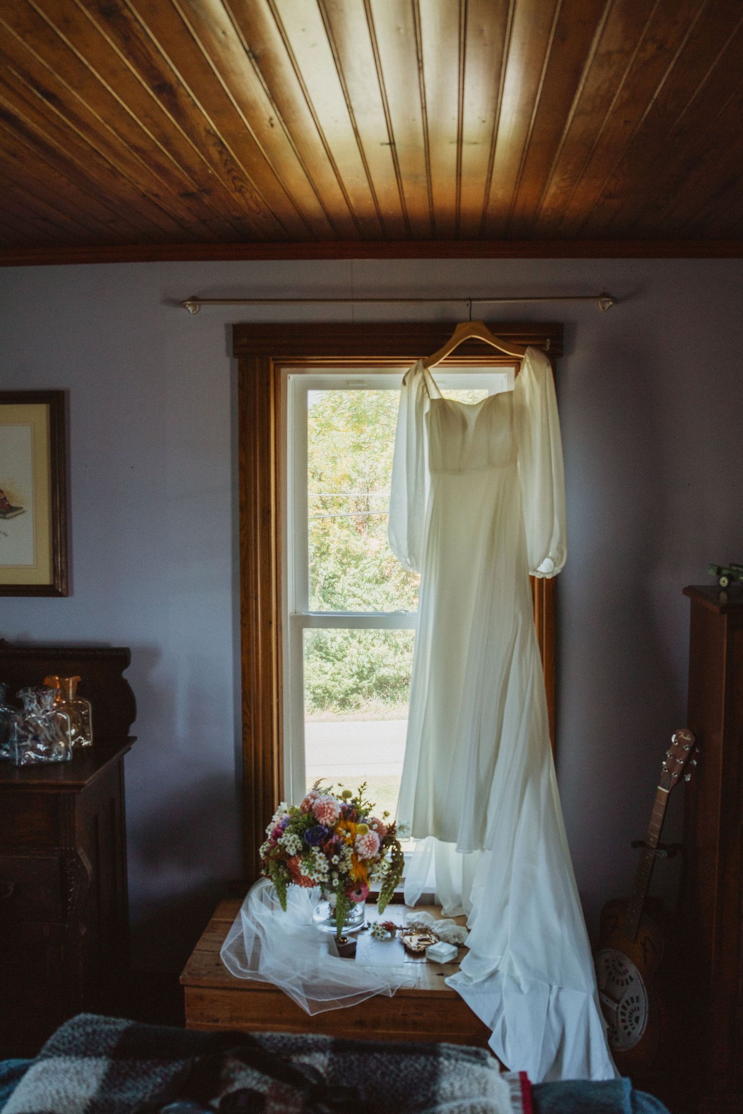 Rustic interior with wooden ceiling, white curtains and natural light streaming through windows.