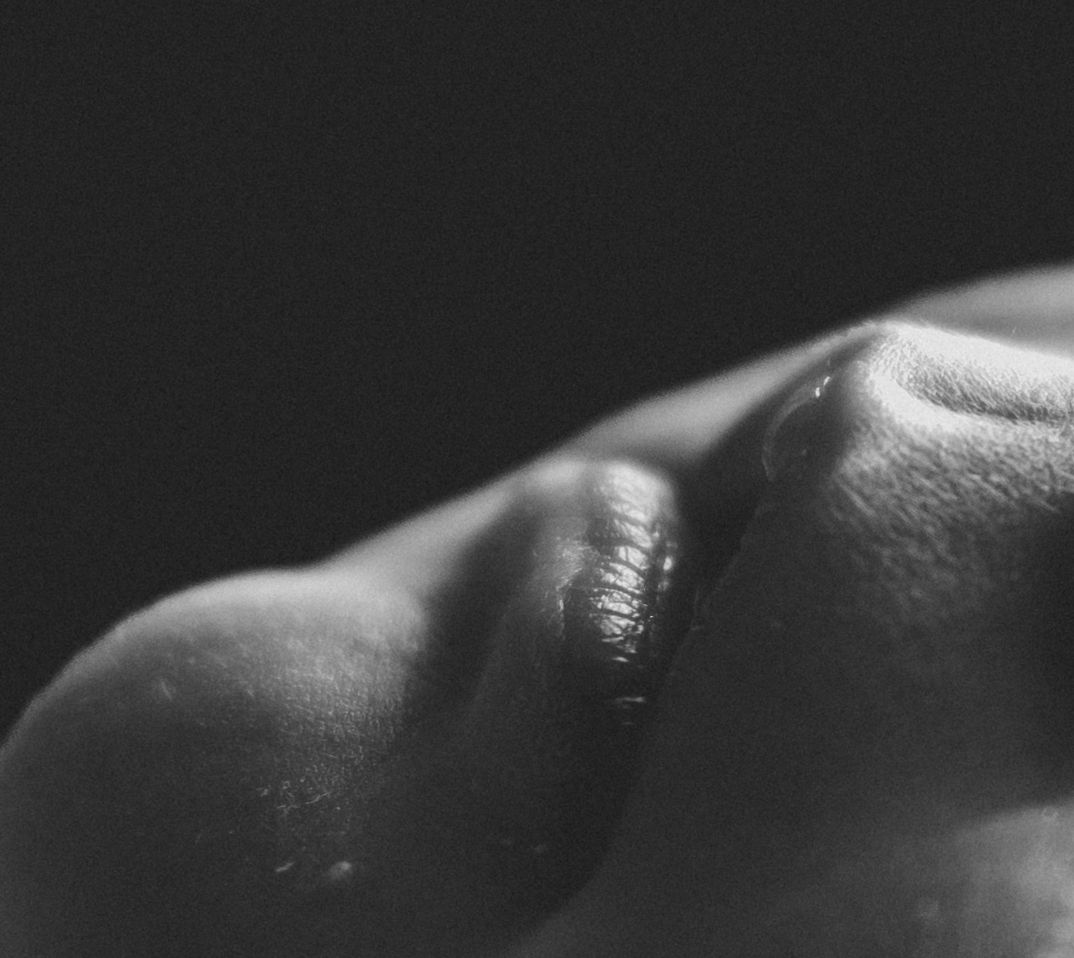Close-up black and white macro photo of human skin texture showing subtle curves and shadows.