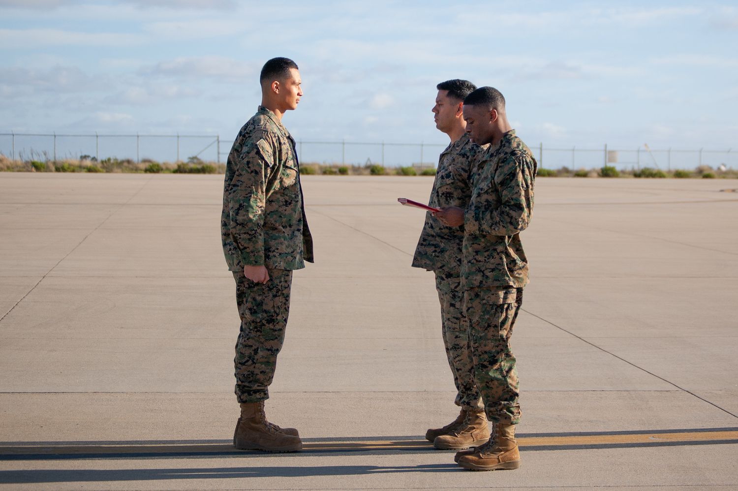 Three US Marines in camouflage uniforms during a promotion.