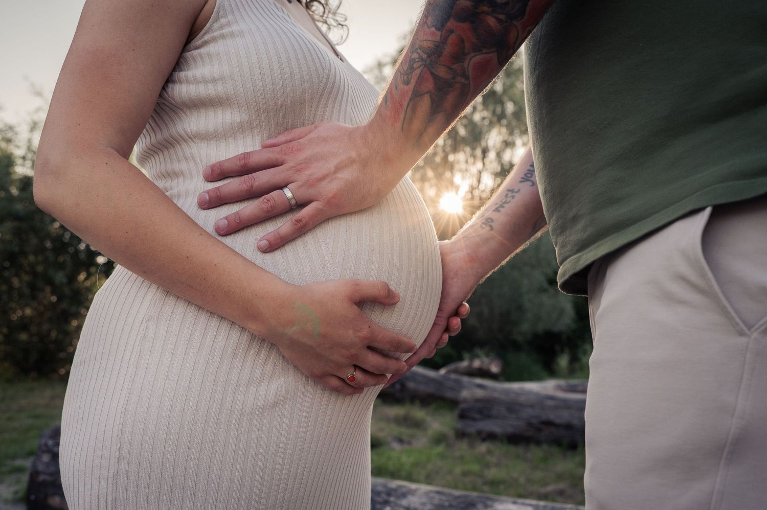 Zwangerschaps fotoshoot. Ouders houden babybuik liefdevol vast. zonsondergang.