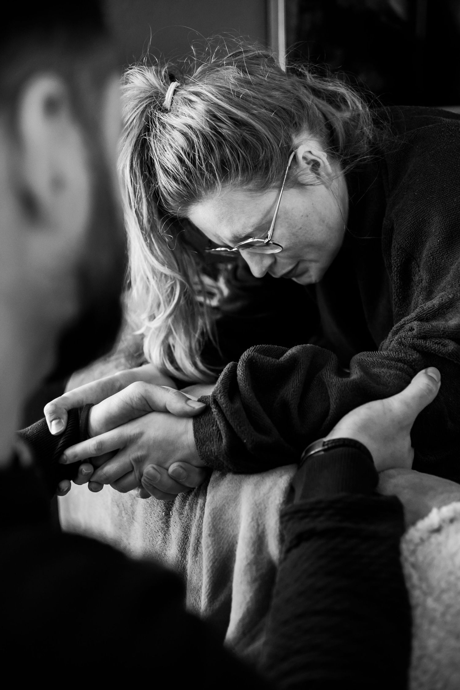 geboorte fotografie detail foto van partner die liefdevol bevallende vrouw steunt