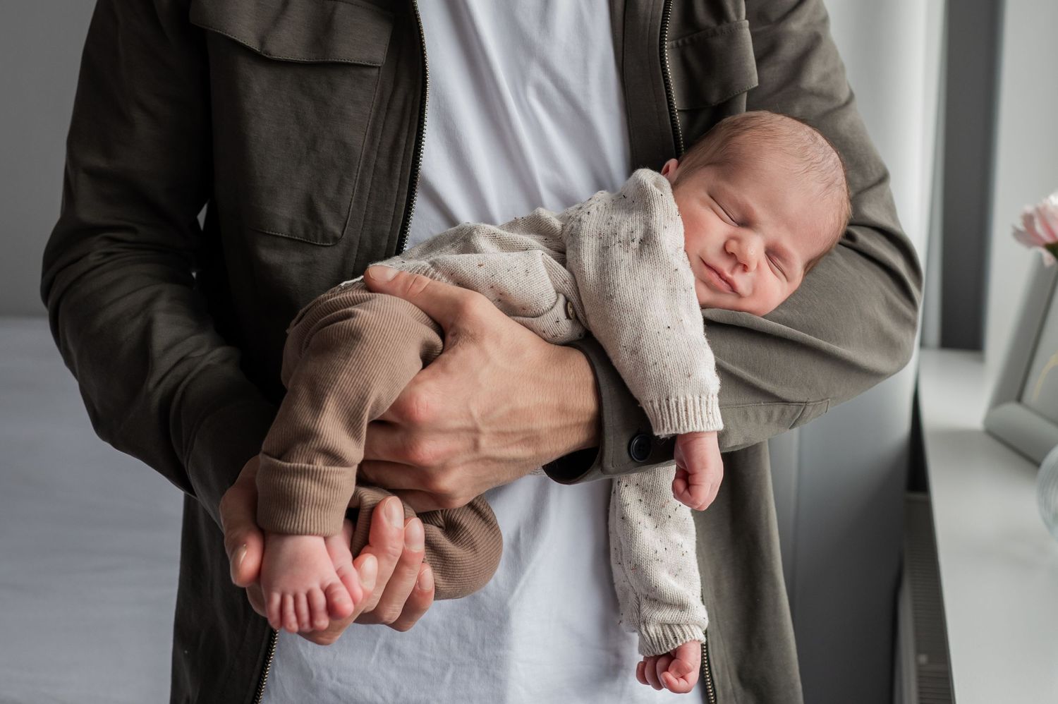 Father holding a sleeping newborn baby securely in both arms during an indoor portrait. Lelystad, Almere, Dronten, Flevoland