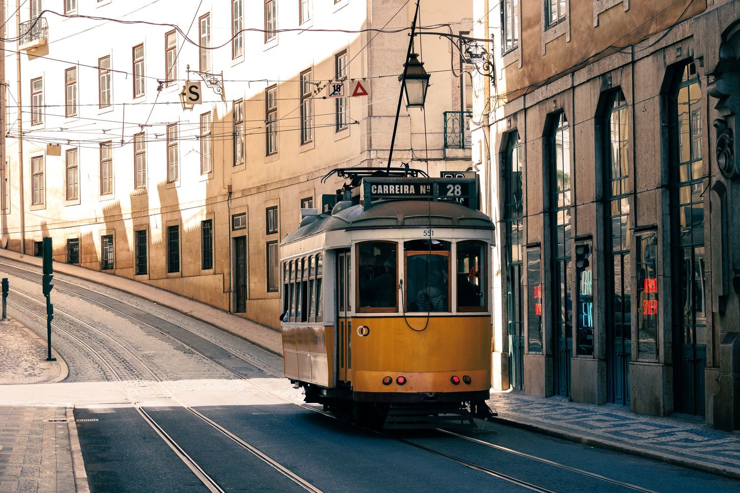 Tram storico giallo tra i vicoli dell'Alfama a Lisbona - Luce del mattino