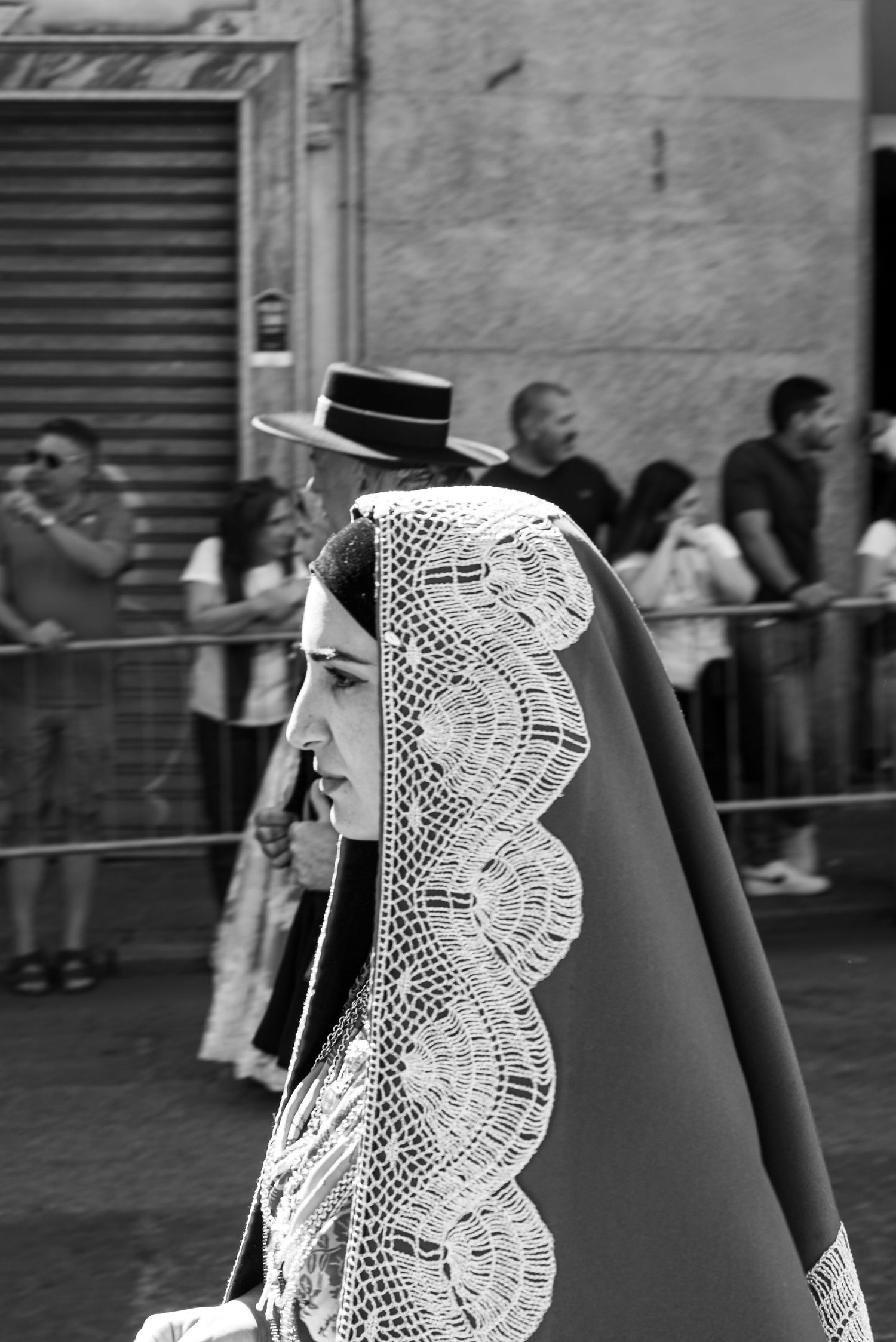 Partecipante alla sfilata del Redentore a Nuoro in abito tradizionale, vista laterale con copricapo ricamato, foto in bianco e nero-MEvisual