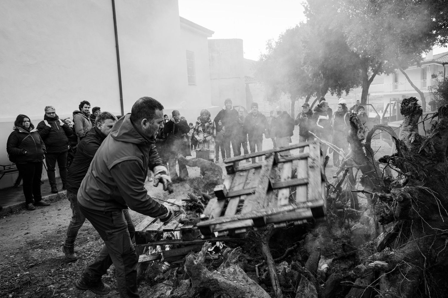 Traditional Mamuthones and Issohadores masks around the fire in Mamoiada, Sardinia - Black and white reportage by Marco Eretta