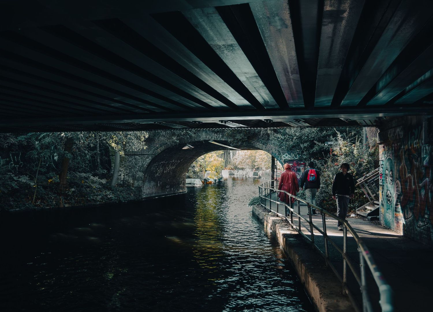 Persone camminano sull'alzaia del canale sotto un ponte con graffiti. People on canal path under bridge with graffiti. MEvisual Marco Eretta