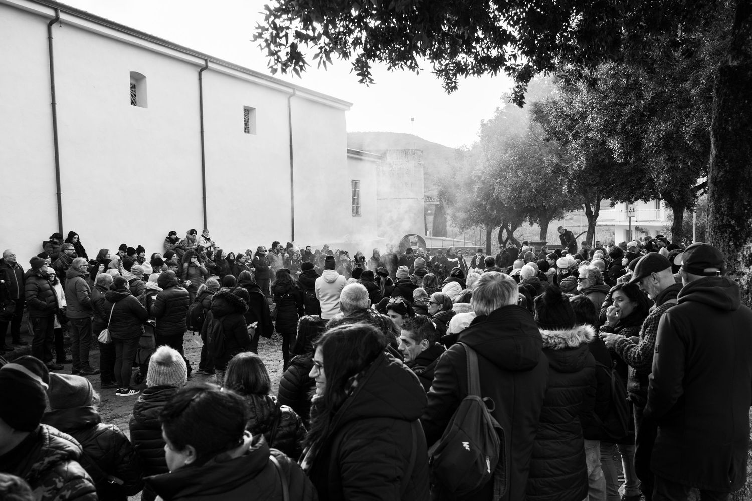 Traditional Mamuthones and Issohadores masks around the fire in Mamoiada, Sardinia - Black and white reportage by Marco Eretta
