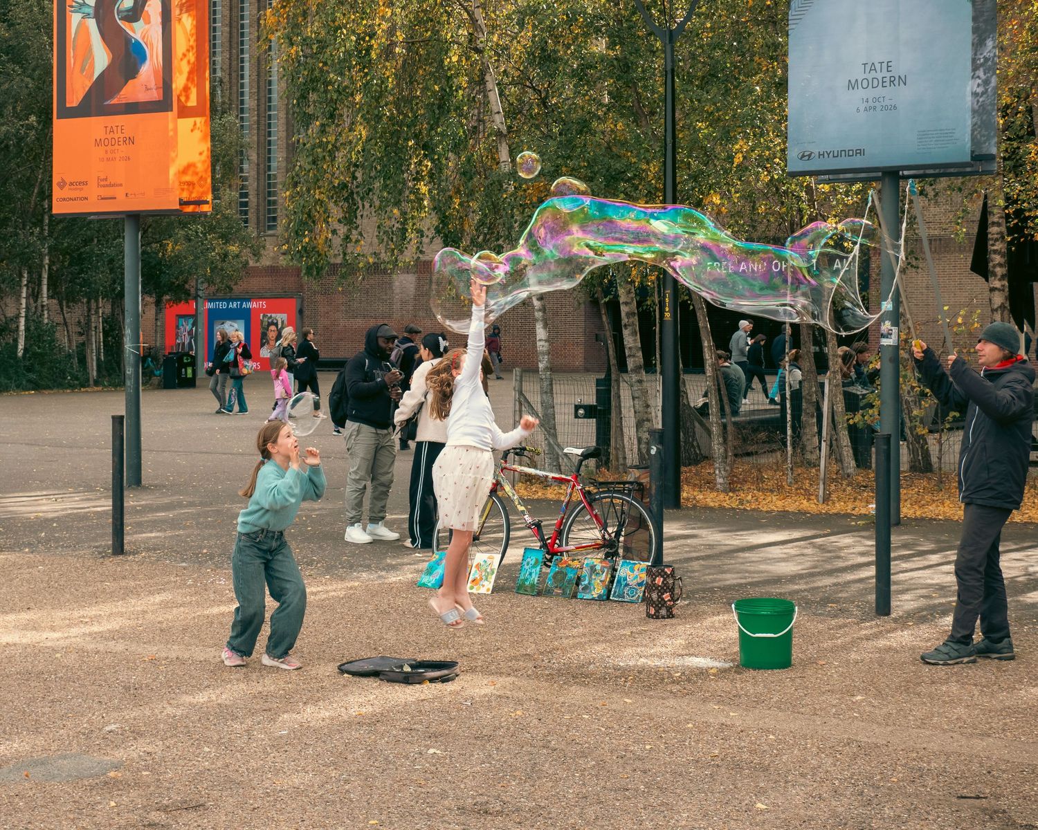 bambine che giocano con bolle di sapone giganti davanti alla Tate Modern. Children playing with giant bubbles outside Tate Modern. ME visual