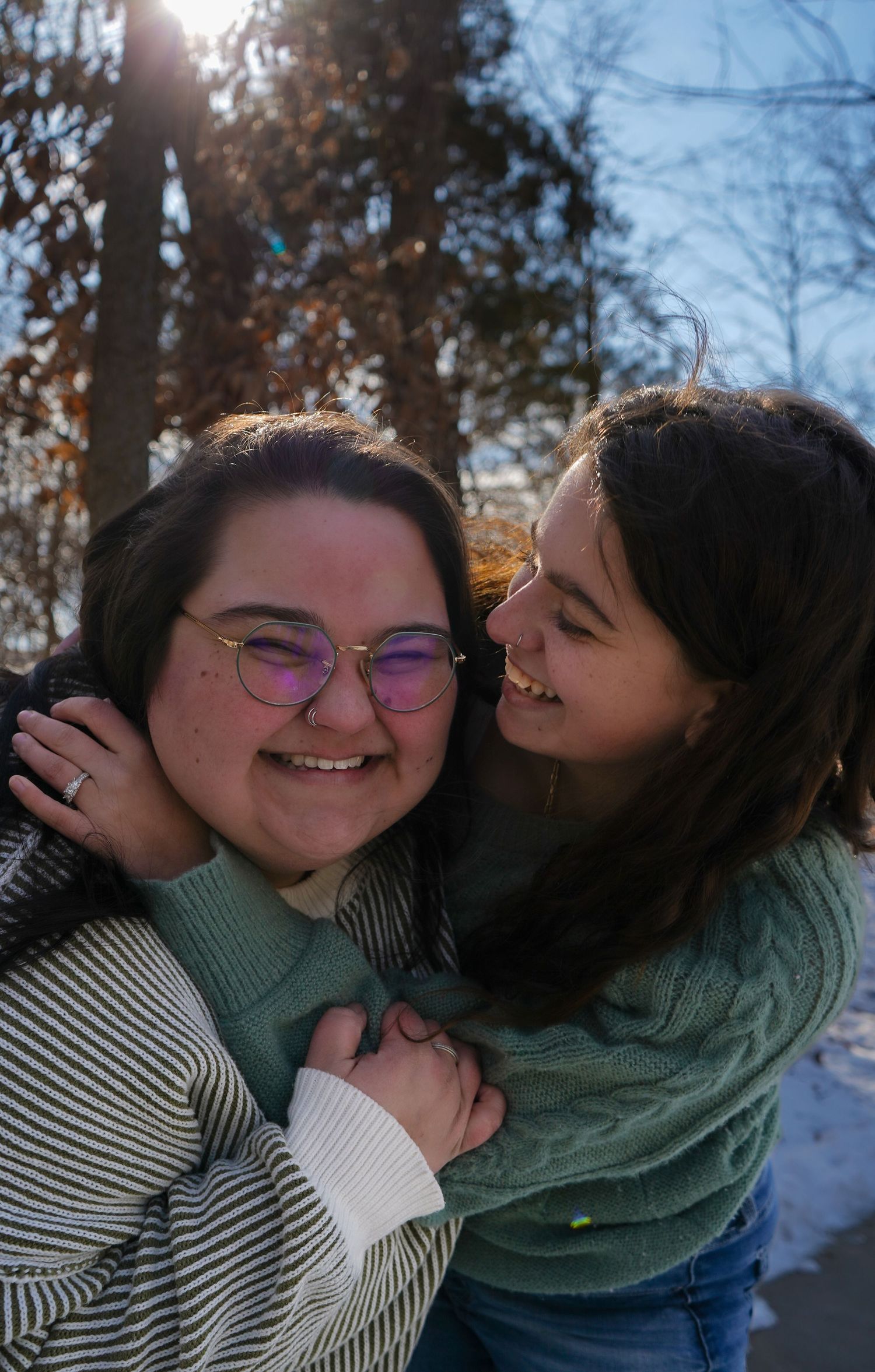 Two young women laughing and embracing warmly outdoors in a sunny winter setting. Bethel Park, Shelby Renee Studios