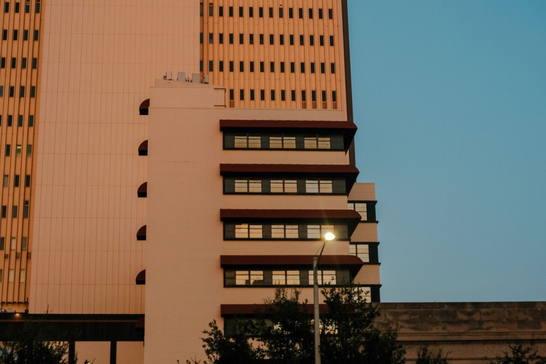 Urban buildings at sunset with warm golden light reflecting off windows against a clear blue sky.