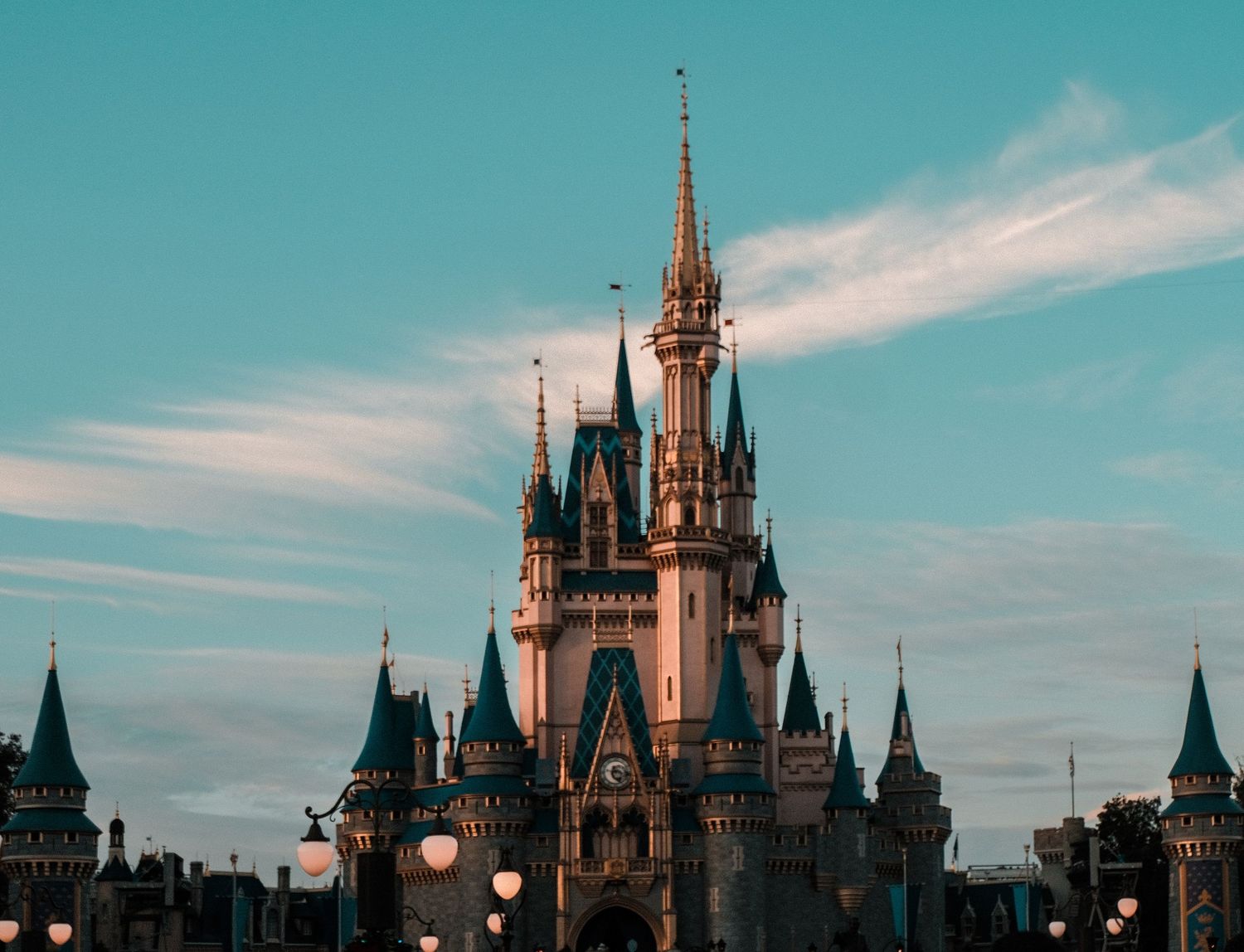 Cinderella Castle at Magic Kingdom, Walt Disney World, against a blue sky with wispy clouds at dusk.