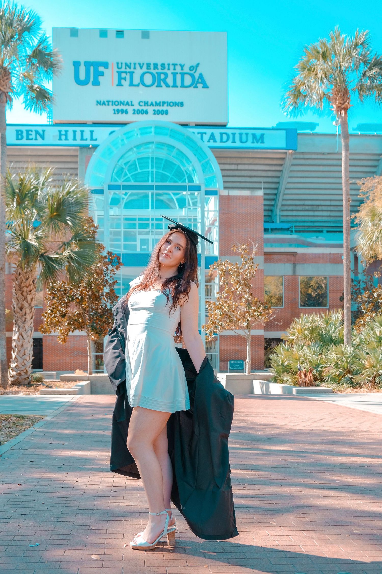Graduate posing in front of Ben Hill Griffin Stadium entrance at UF.