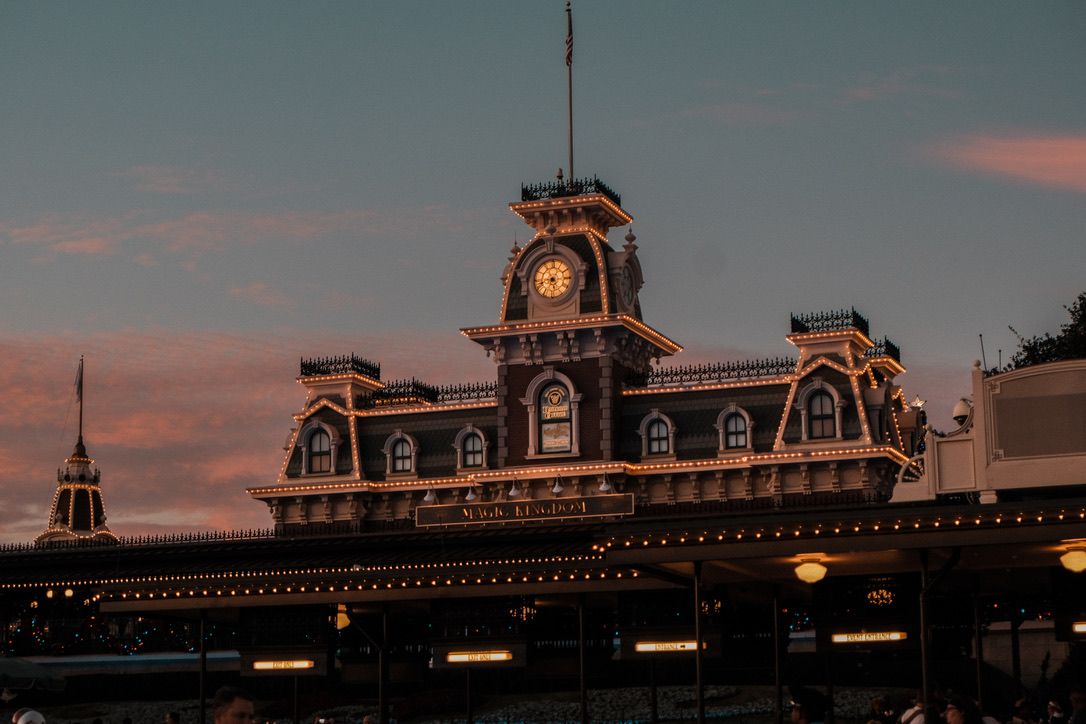 Historic clock tower building at sunset with warm golden light illuminating ornate Victorian architecture against a pink and blue sky.