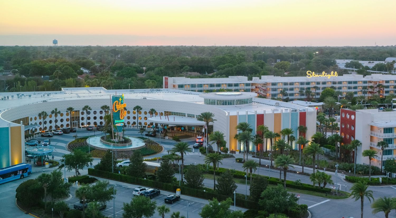 Aerial sunset view of a colorful resort hotel complex surrounded by palm trees in Orlando, Florida.