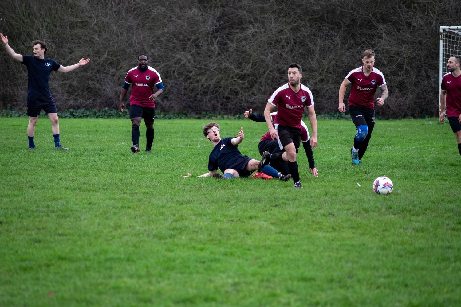 Football tackle during match with players competing for ball in Greater London, UK