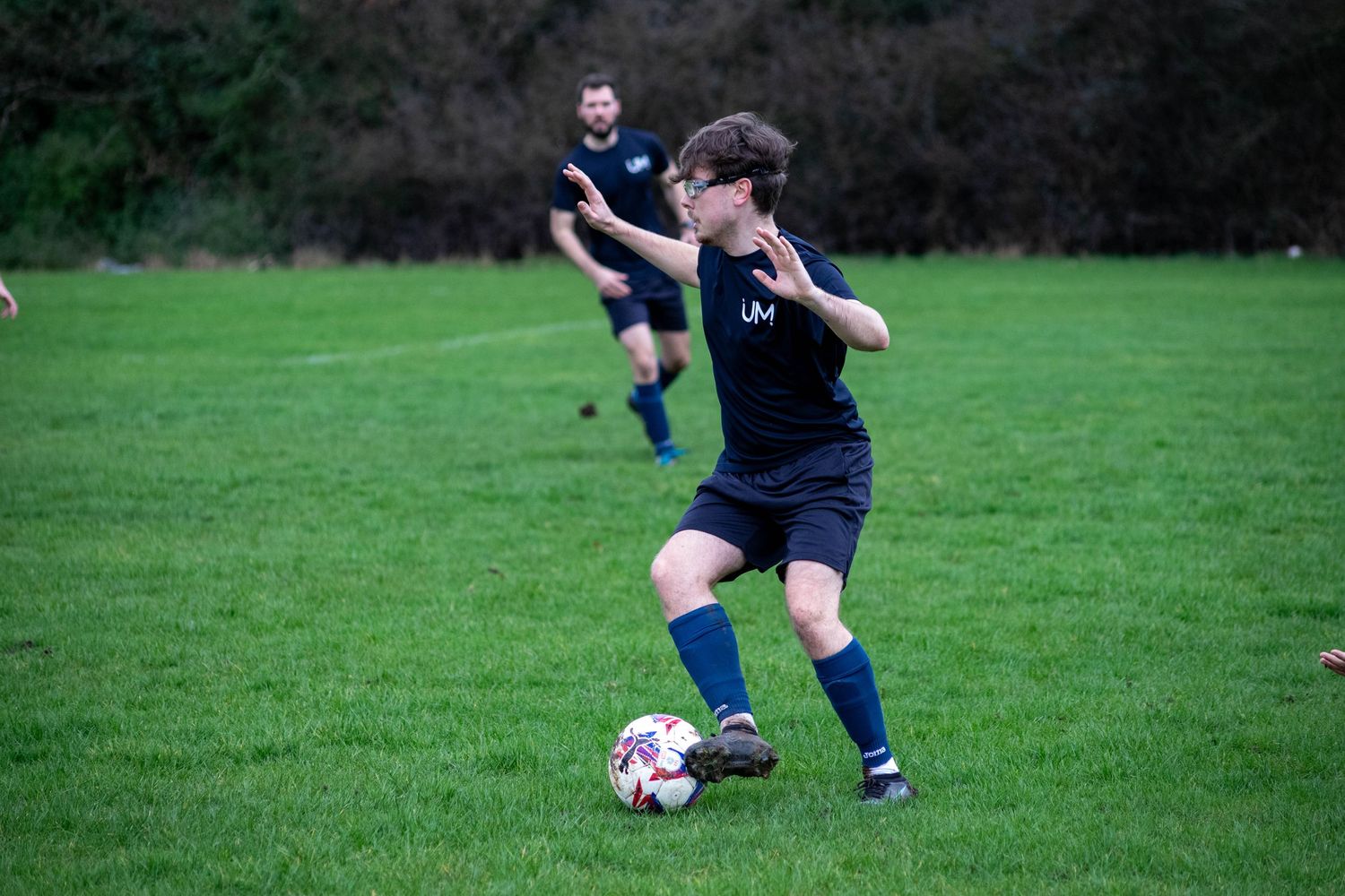 Football player dribbling ball during match with action sports photography in London, UK
