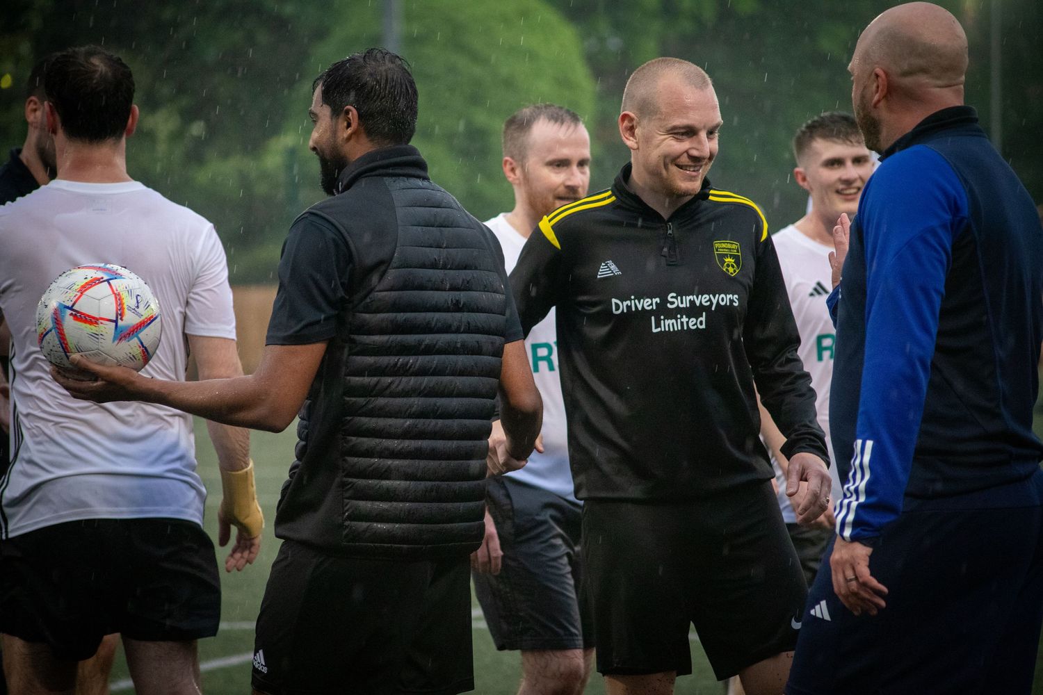 Football team players and coach discussing tactics during training session in North West London, UK