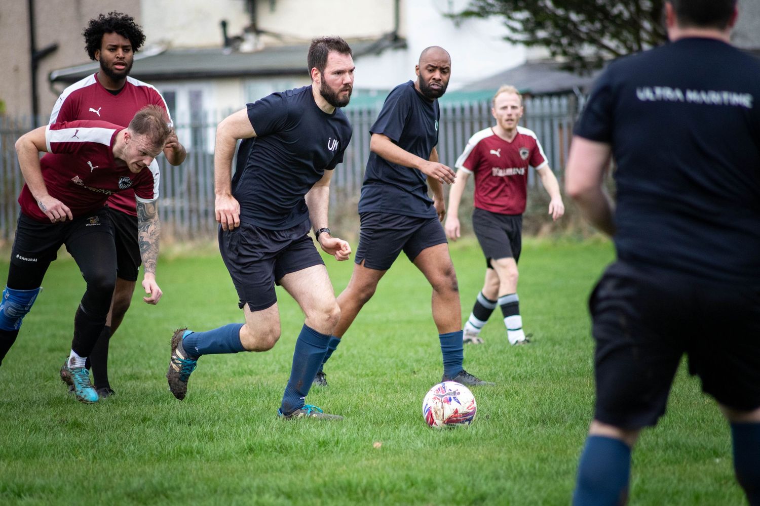 Football players running and competing for ball during match with action sports photography in London City, UK
