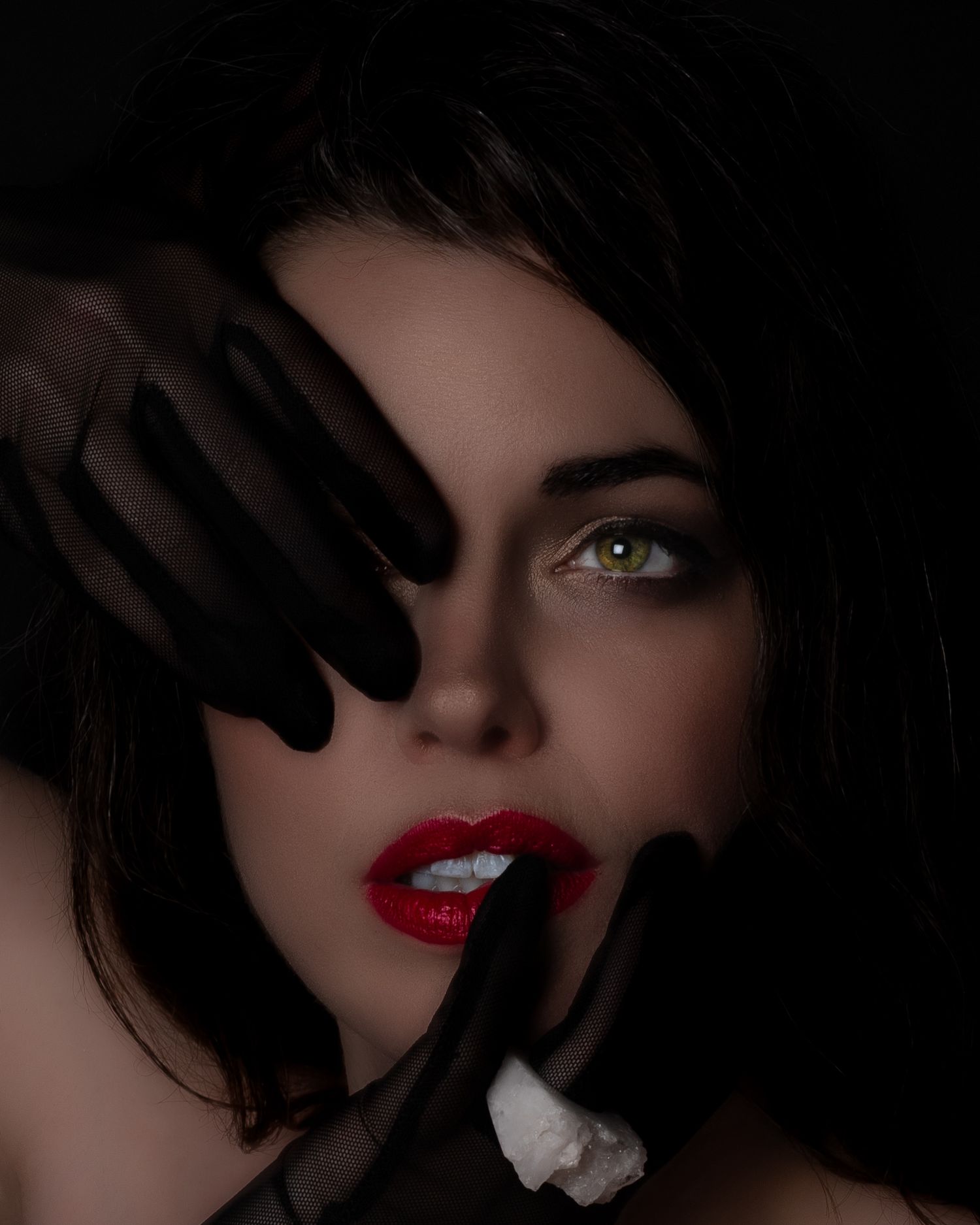A striking beauty portrait of a dark-haired woman with bold red lips and green eyes in black gloves. Ottawa creative editorial fashion art
