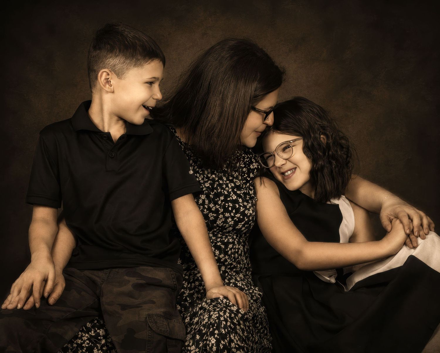 A mother smiles warmly with her two children in a studio portrait. an Ottawa studio Family fine art portrait.