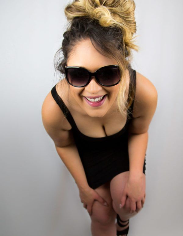 Smiling blonde woman in black tank top wearing sunglasses, shot from above.