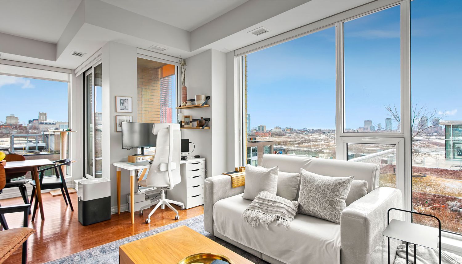 Professional real estate photography of a modern Ottawa condominium living room featuring floor-to-ceiling windows and city skyline views.