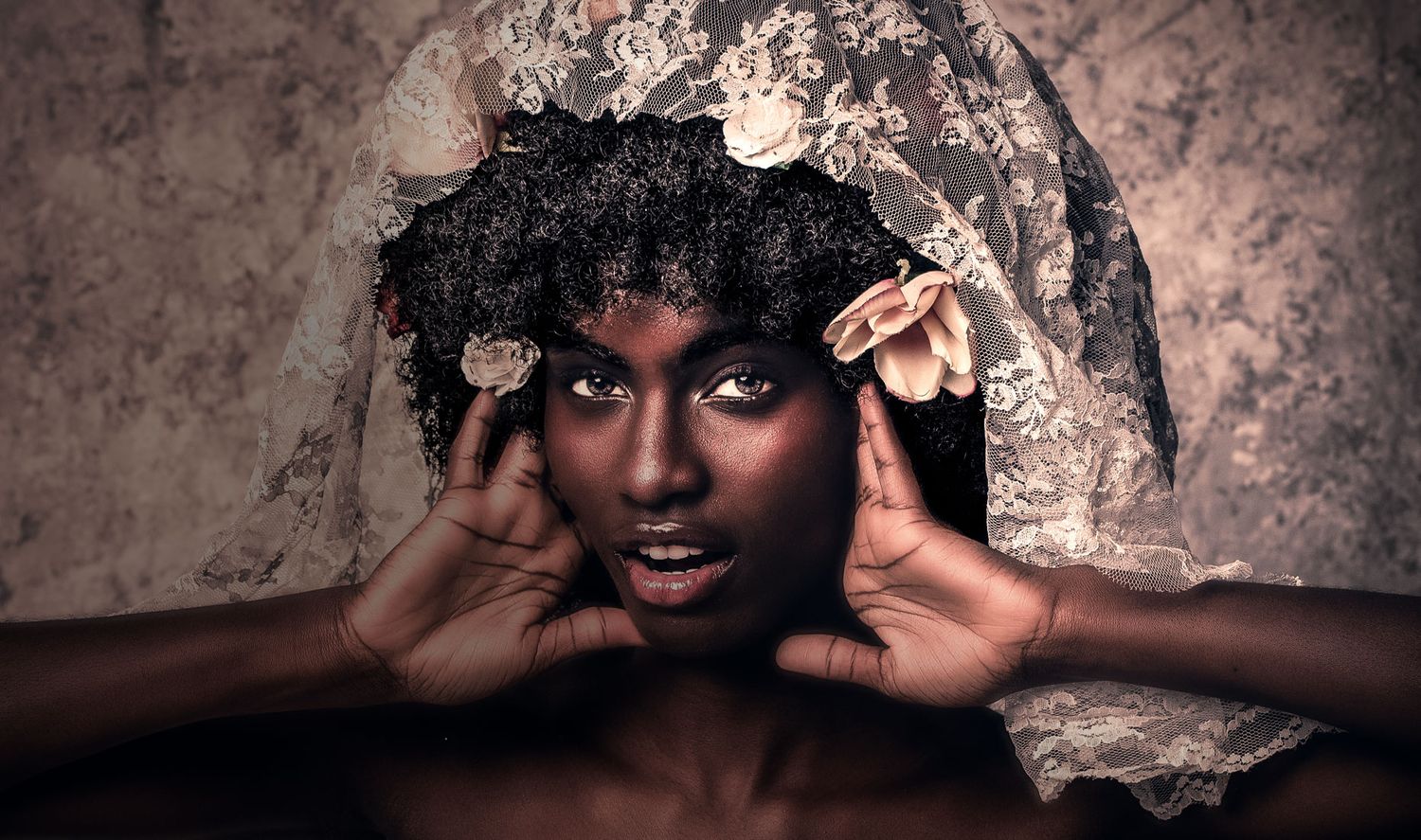 Artistic portrait of a young Black woman wearing a lace veil headpiece with floral accents.