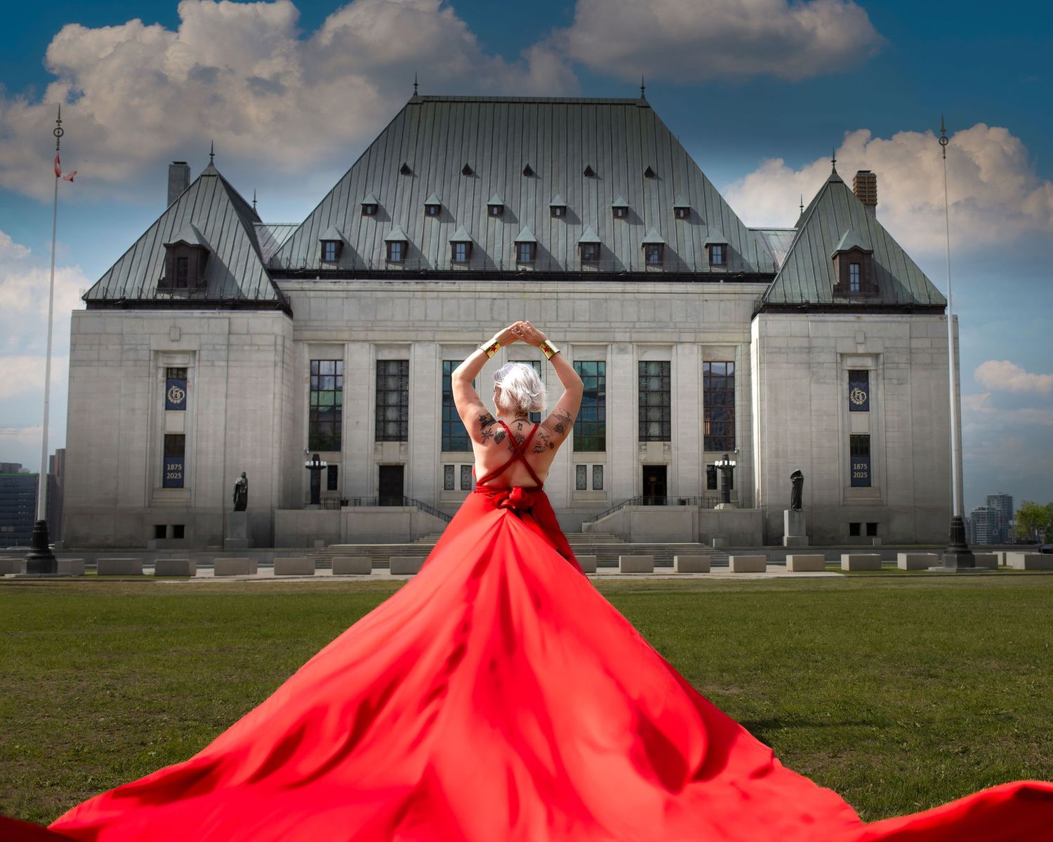 Woman in flowing red gown poses gracefully before the Supreme Court of Canada on a sunny day. Ottawa flying dress photography.
