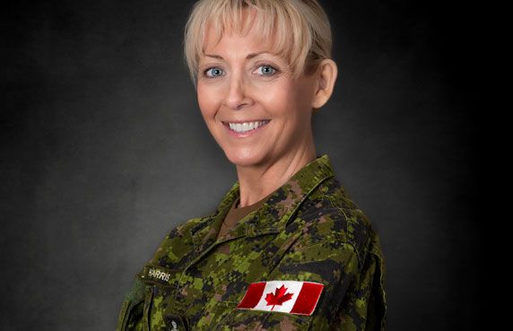 Female Canadian Armed Forces soldier smiling in camouflage uniform with Canadian flag patch.