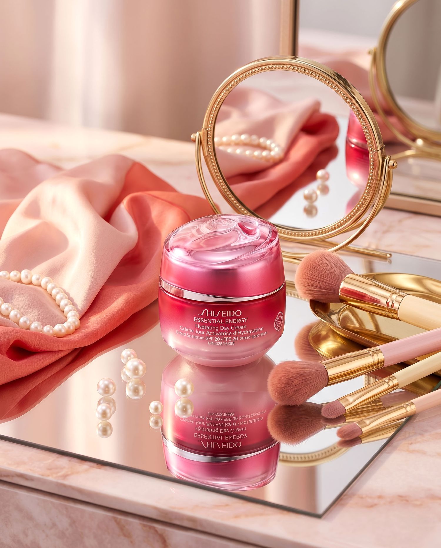 Shiseido Essential Energy cream jar with gold makeup brushes and pearl necklace on mirror.