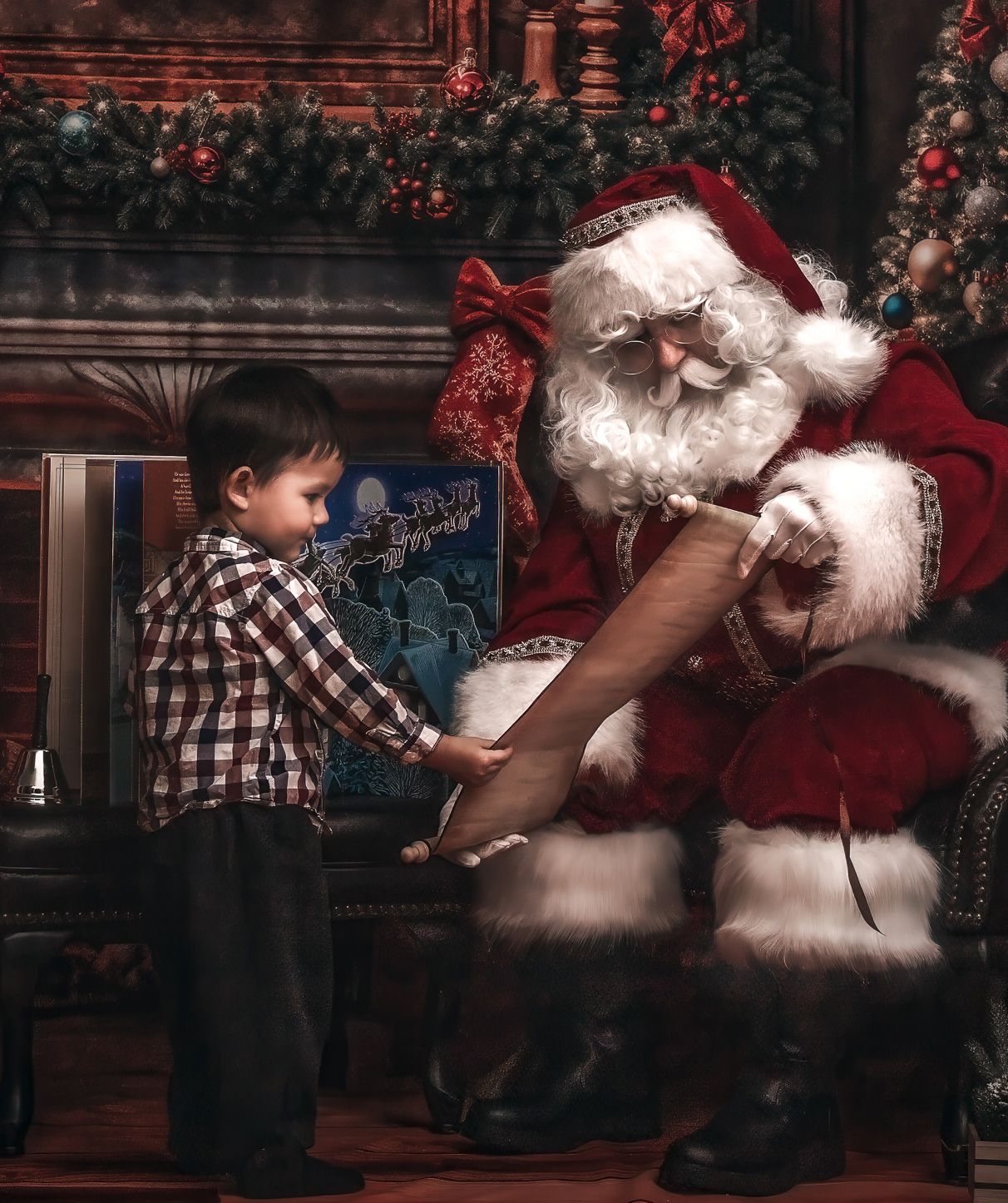 Young boy reviewing Santa Claus's naughty and nice list by a decorated Christmas fireplace.