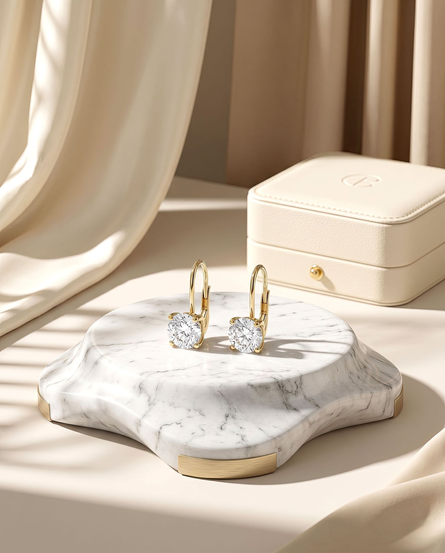 Gold diamond drop earrings elegantly displayed on white marble tray beside cream jewelry box in soft light.