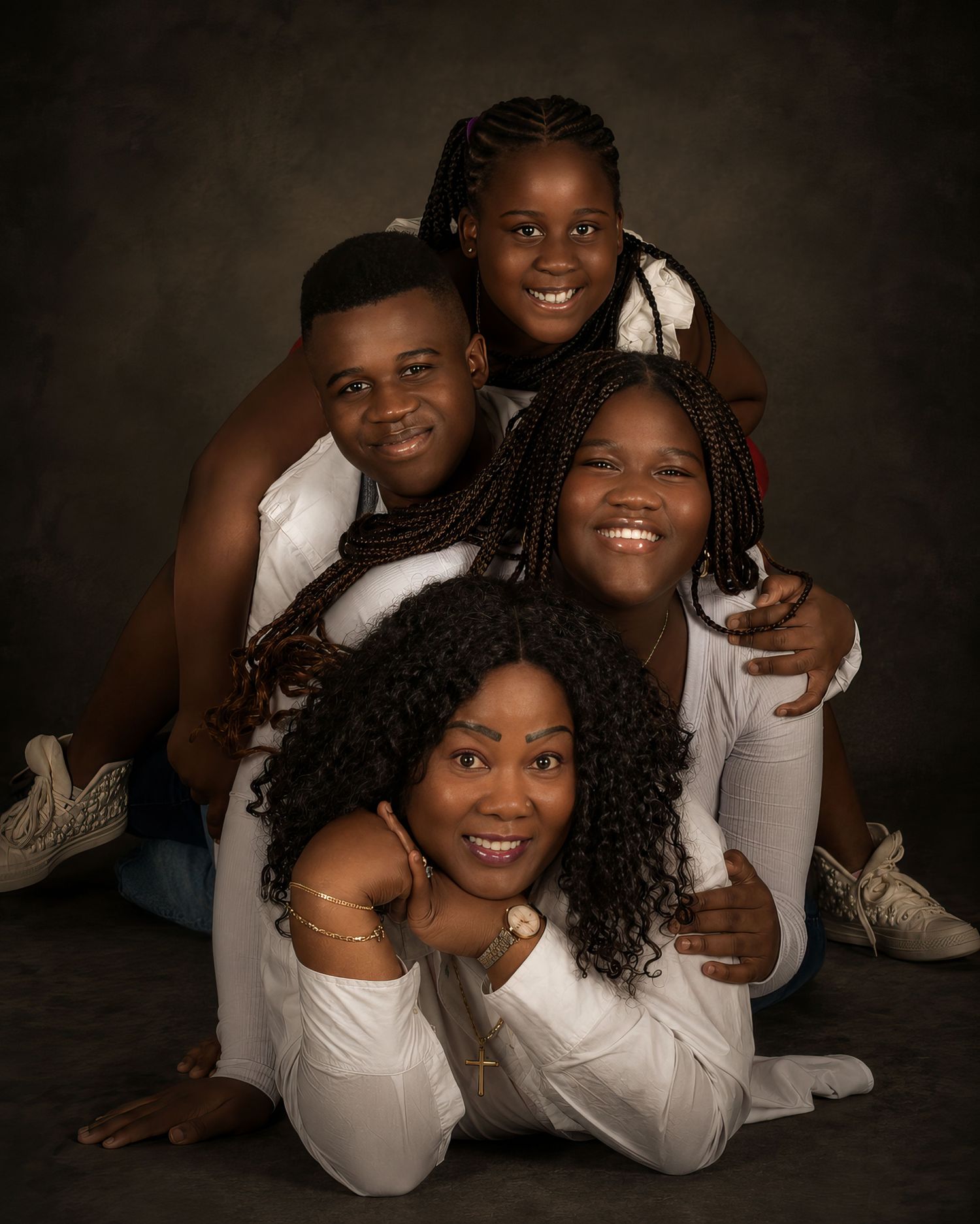 A family of four stacks playfully in white outfits for a studio portrait. an Ottawa studio Family fine art portrait.