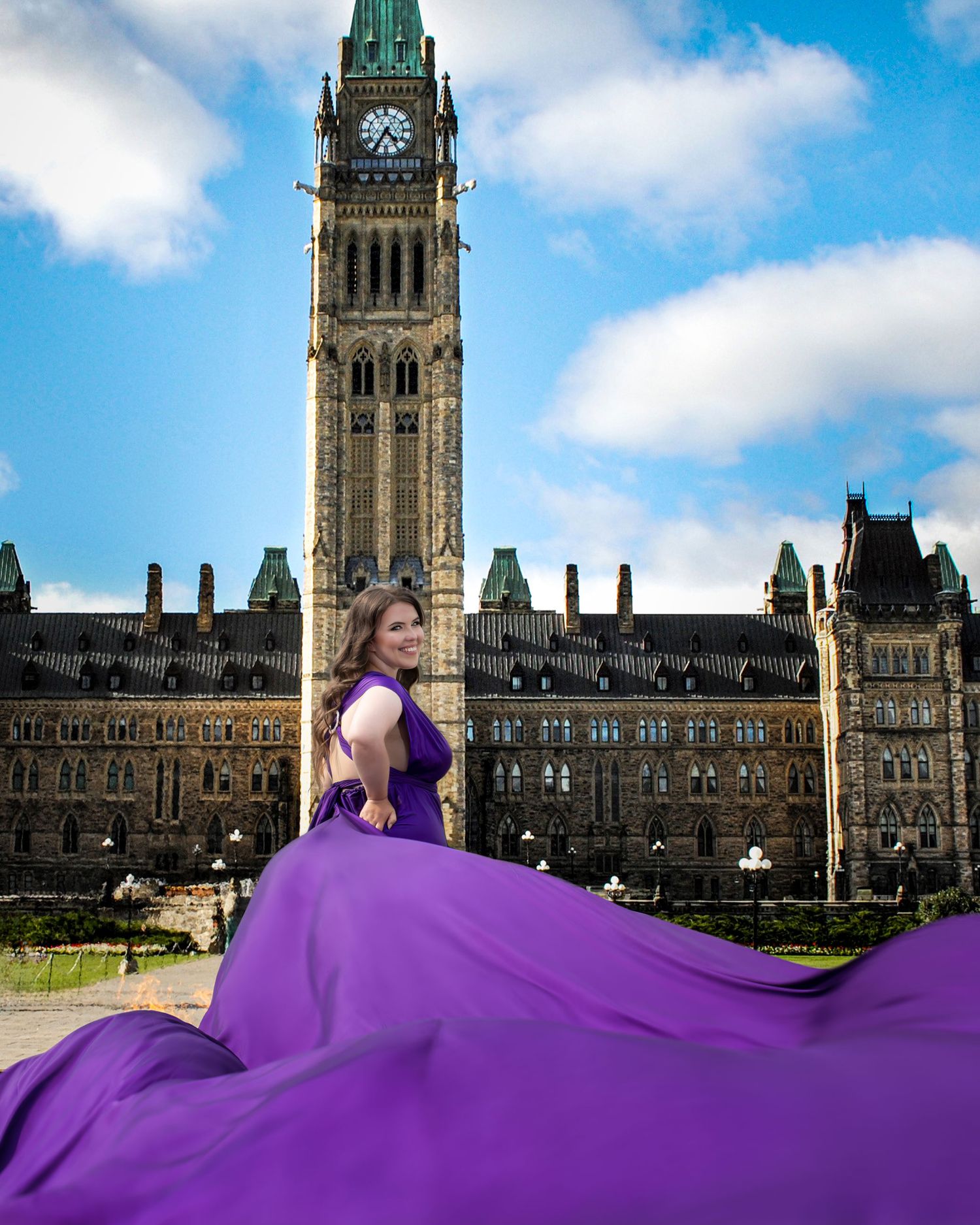 Woman in purple flying dress poses before Canadian Parliament Peace Tower on sunny day. Ottawa flying dress photography.
