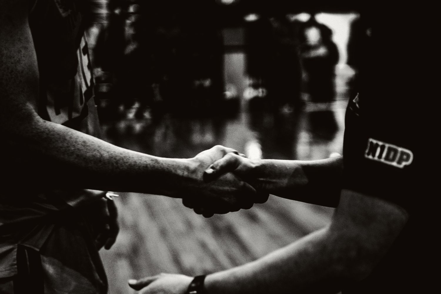 An NBL 1 player and coach shaking one another's hands after a basketball game.