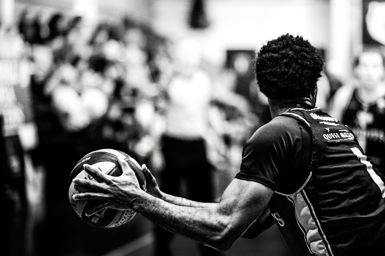 An NBL 1 basketball player holding the basketball out to his side during a game.