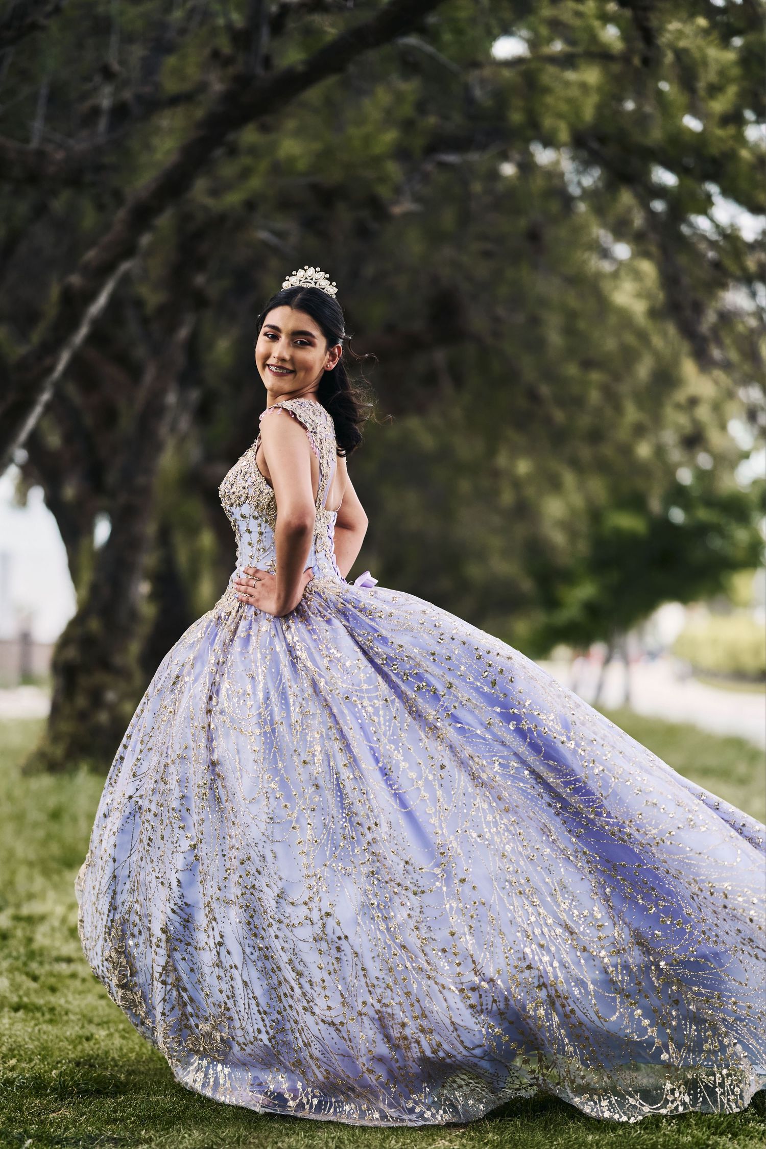 Lavender ball gown with delicate floral details photographed in an outdoor garden setting.