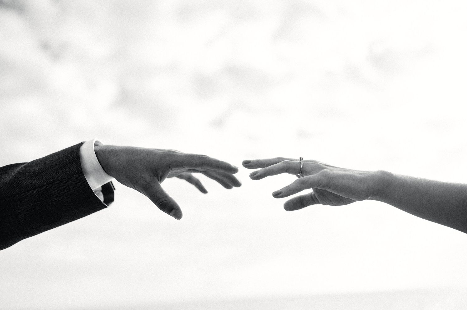 Silhouettes of hands reaching out to each other against a bright background.