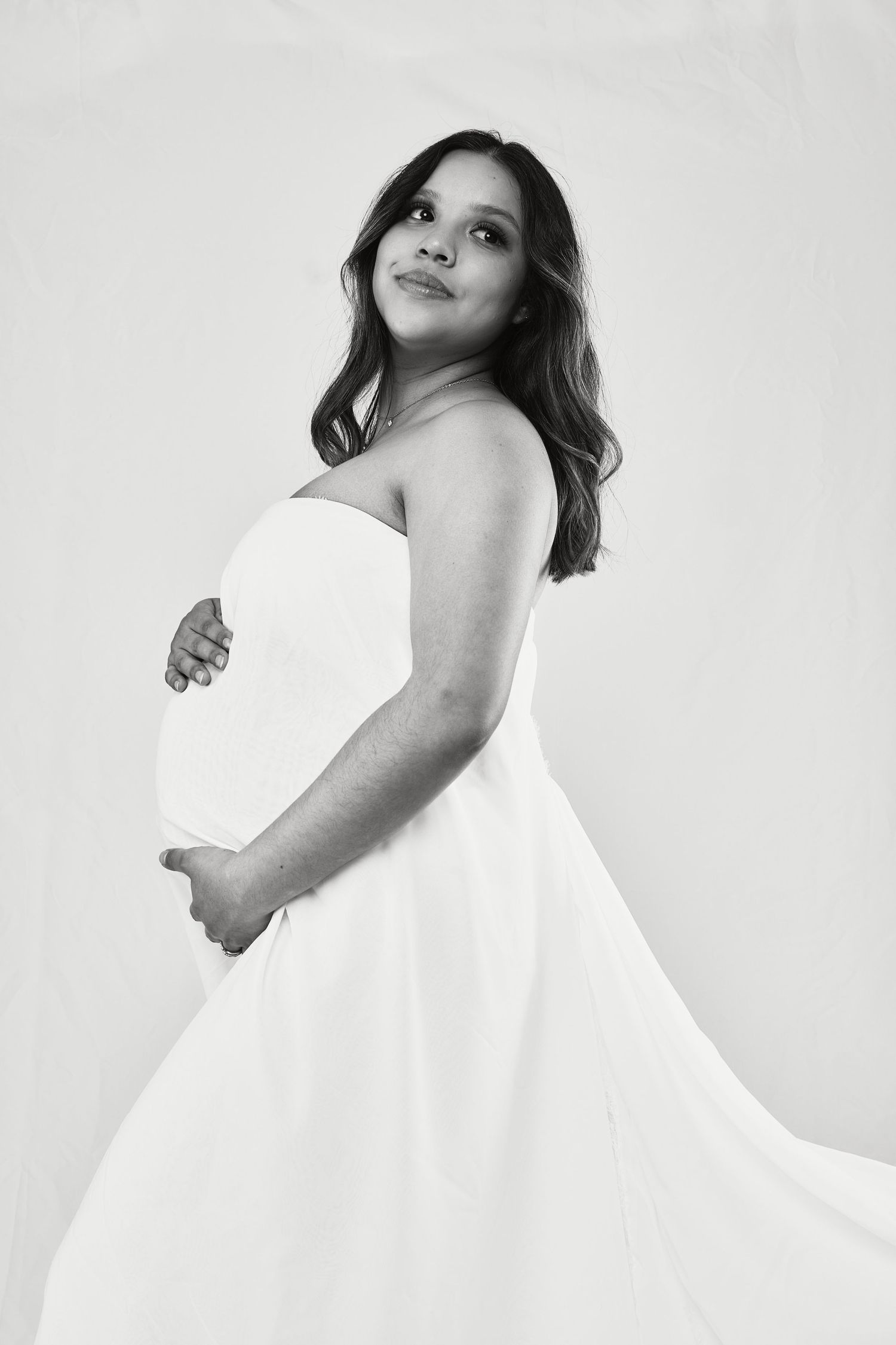 Artistic maternity portrait series in white fabric against light background.